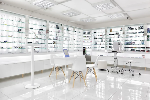 Vitríny s brýlemi a doplňky, bílý stolek se židlemi