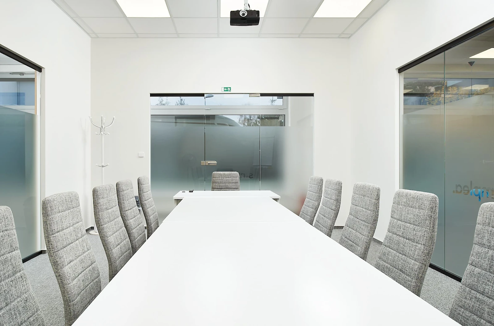 Zasedací místnost s dlouhým bílým stolem a šedými židlemi