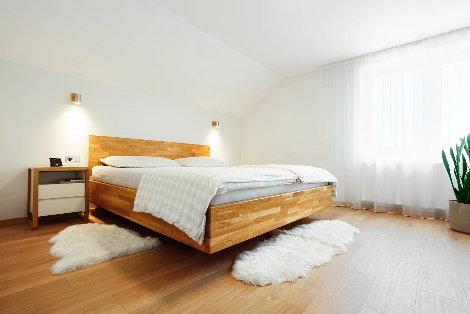 Světlá ložnice s dřevěnou postelí